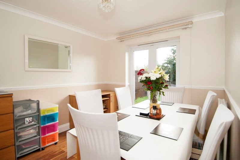 Bright dining room with white table, wooden chairs, mirror, and garden view through glass doors