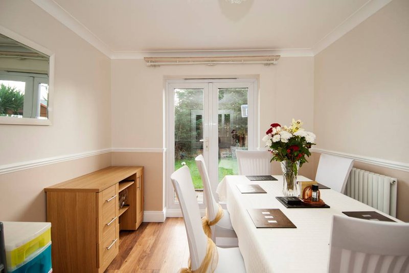 Bright dining room with white table, wooden chairs, and garden view through glass doors