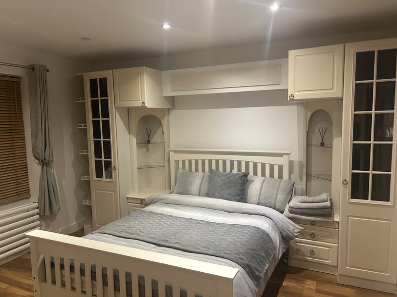 Modern bedroom with built-in white cabinetry, double bed, gray bedding, and recessed lighting