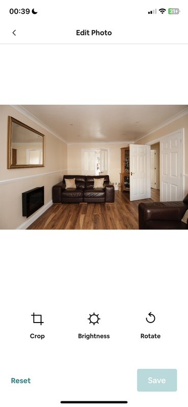 Spacious living room with fireplace, mirror, dark sofa and wooden flooring