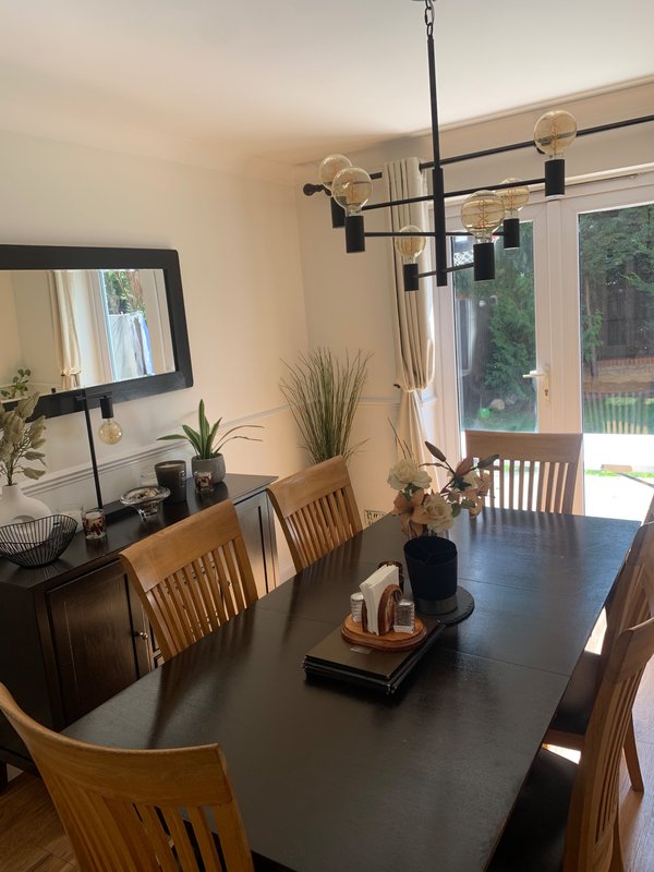 Modern dining room with black table, wooden chairs, pendant lighting and garden view