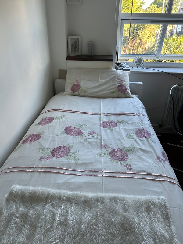 Single bed with patterned duvet and pillows, window with countryside view