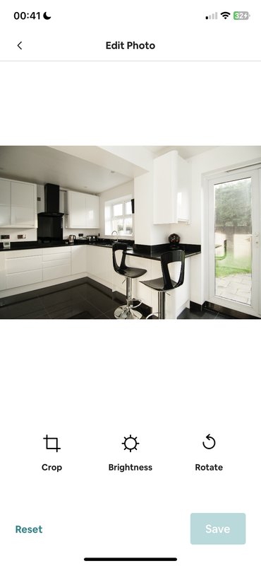Modern kitchen with white cabinetry, black countertop, island seating, and glass door to garden