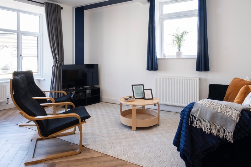 Spacious studio apartment with bed, lounge chair, TV and large windows