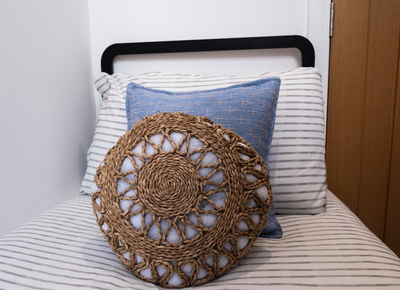 Bedroom with black metal bed frame, striped white bedding, and decorative woven and blue pillows