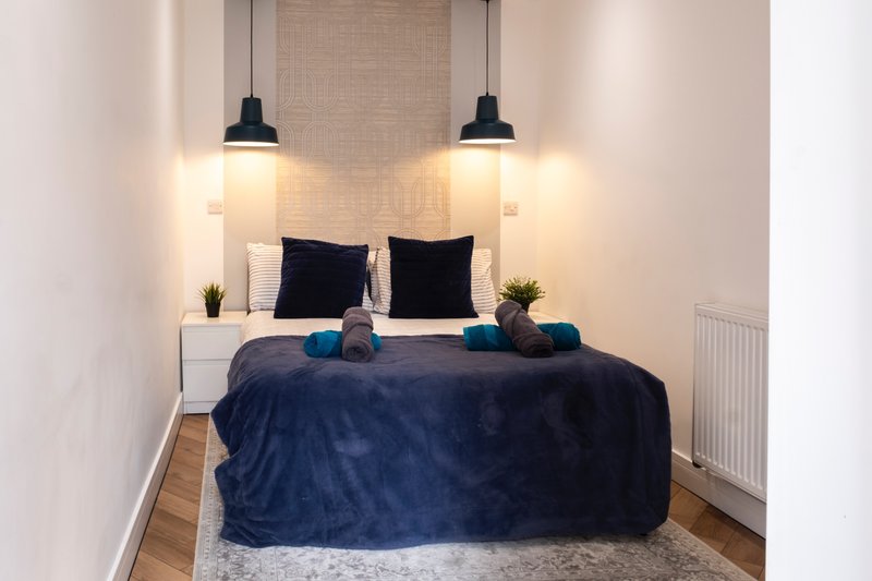 Modern bedroom with double bed, black pillows, pendant lighting and neutral decor