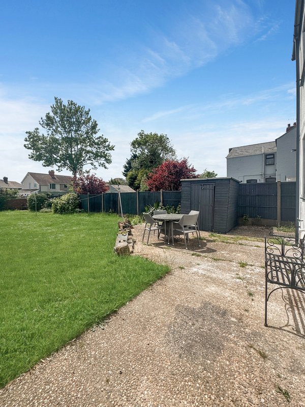 Garden patio area with seating, lawn, trees and neighboring properties visible