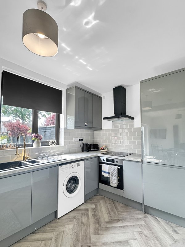 Modern kitchen with grey cabinetry, white subway tiles, stainless steel appliances and window.