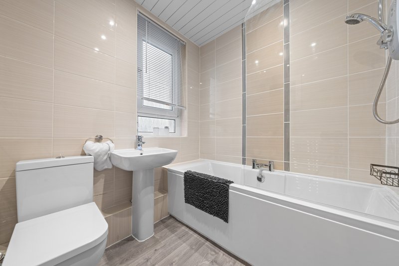 Modern bathroom with white suite, shower enclosure, pedestal sink and window