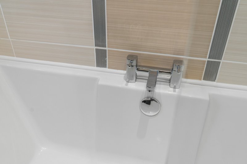 Modern bathroom sink with chrome tap fixtures and beige tiled splashback