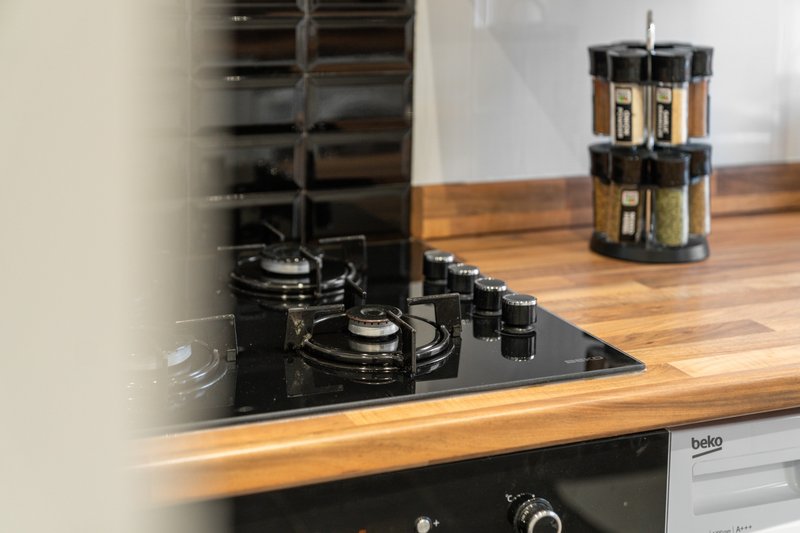Modern kitchen with black gas cooktop, wooden countertop, and spice carousel