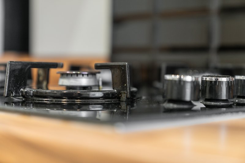 Kitchen stovetop with knobs and controls, wooden countertop visible