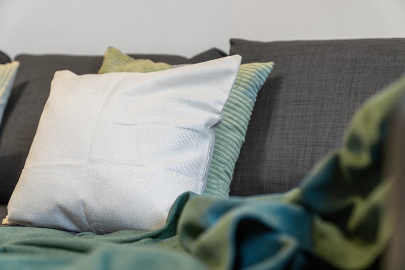 Gray sofa with white and striped cushions and folded blankets