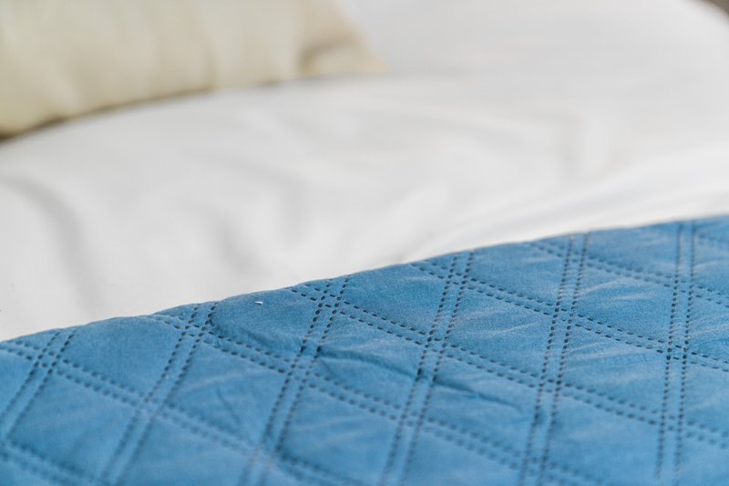 Close-up of blue quilted bedding with white pillows on a bed
