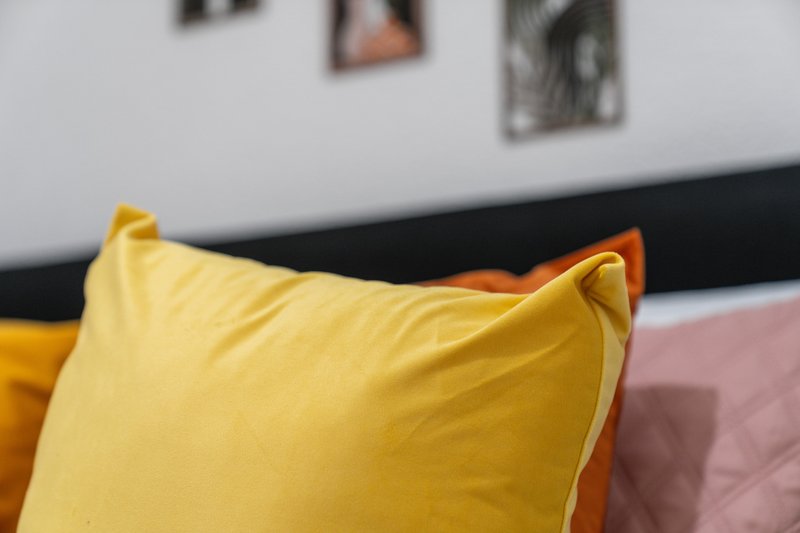 Close-up of yellow decorative cushion on sofa with wall art in background