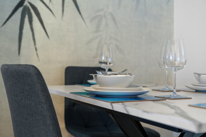 Modern dining table set with place settings, glassware, and hanging plant decoration