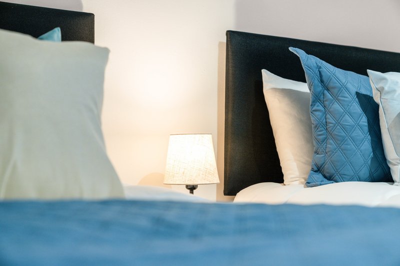 Modern bedroom with double bed, blue pillows, bedside lamp and black headboard
