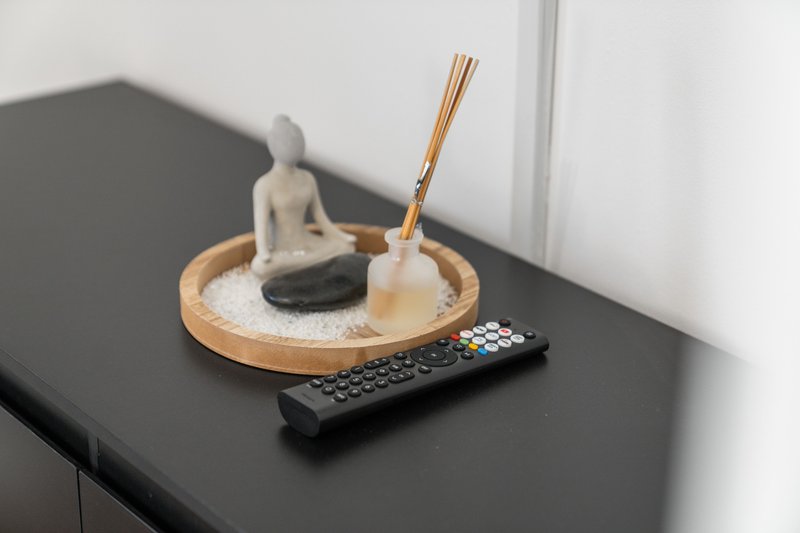 Black shelf with decorative items including figurine, incense holder, brush and remote control
