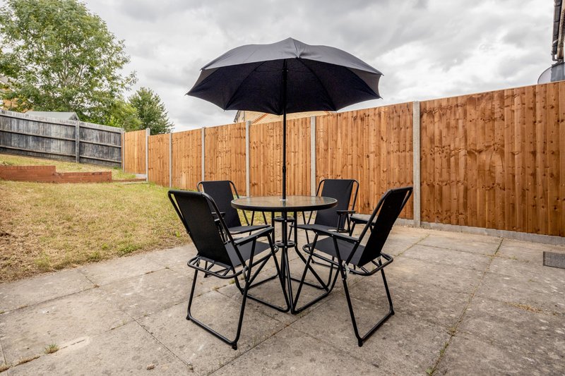 Outdoor patio area with black umbrella, round table and four folding chairs
