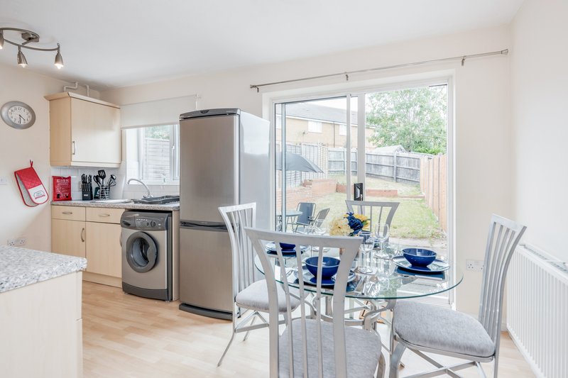 Open-plan kitchen and dining area with appliances, dining table, and garden view through patio doors