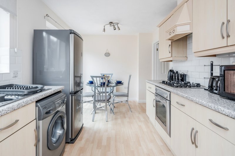 Modern kitchen with cream cabinets, stainless steel appliances, dining table and chairs