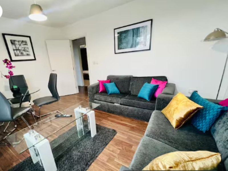Modern living room with grey sofas, colorful cushions, wooden floor and framed wall art