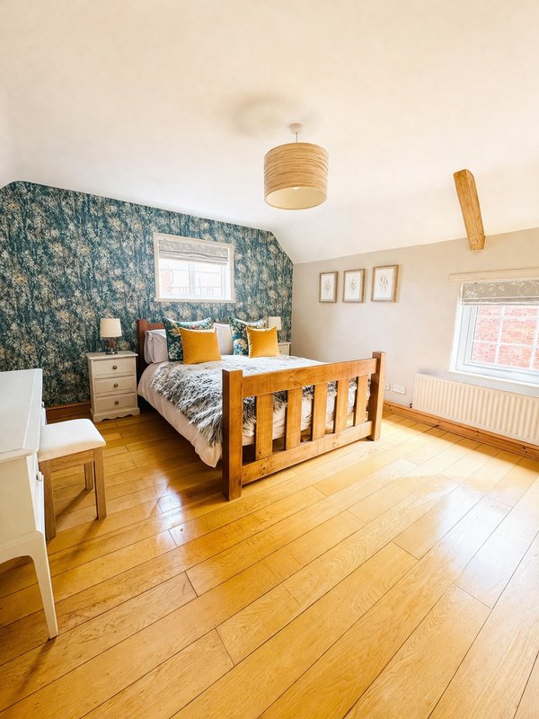 Bright bedroom with wooden bed, patterned accent wall, wooden floor and pendant light