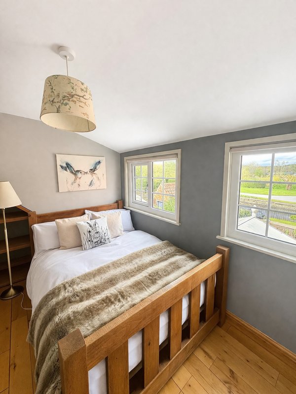 Bedroom with wooden bed, gray and white walls, pendant lamp, bedside table and windows.