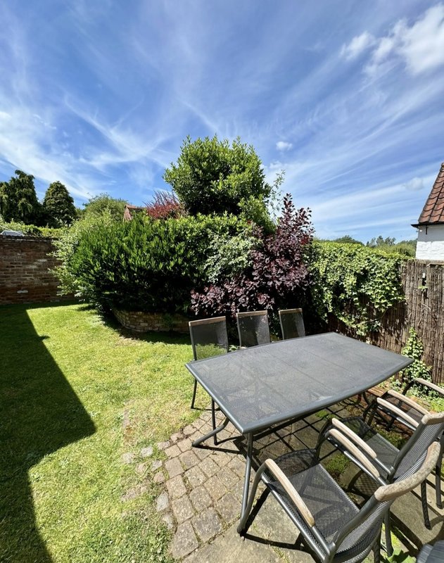 Outdoor garden patio with dining table, chairs and manicured lawn