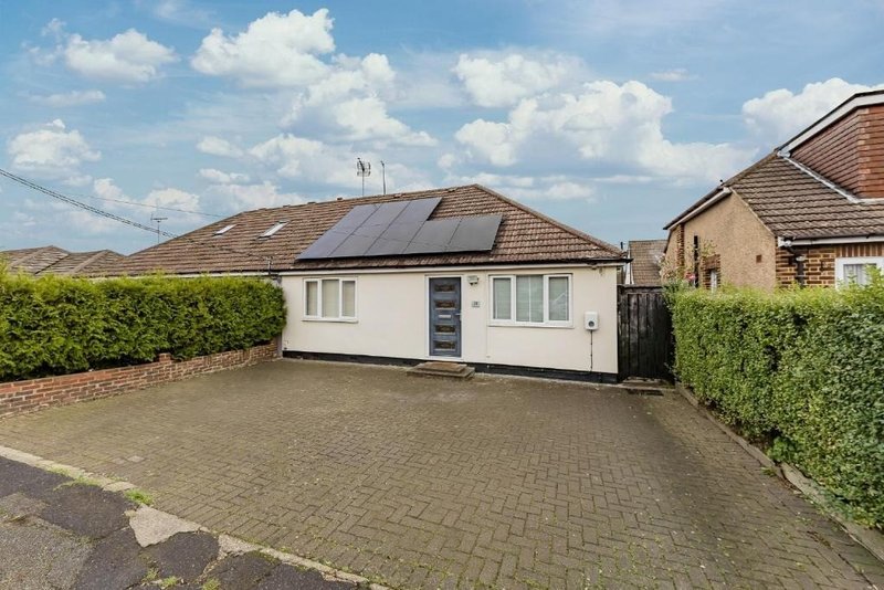 Single-storey bungalow with driveway, brick boundary wall and hedge fencing