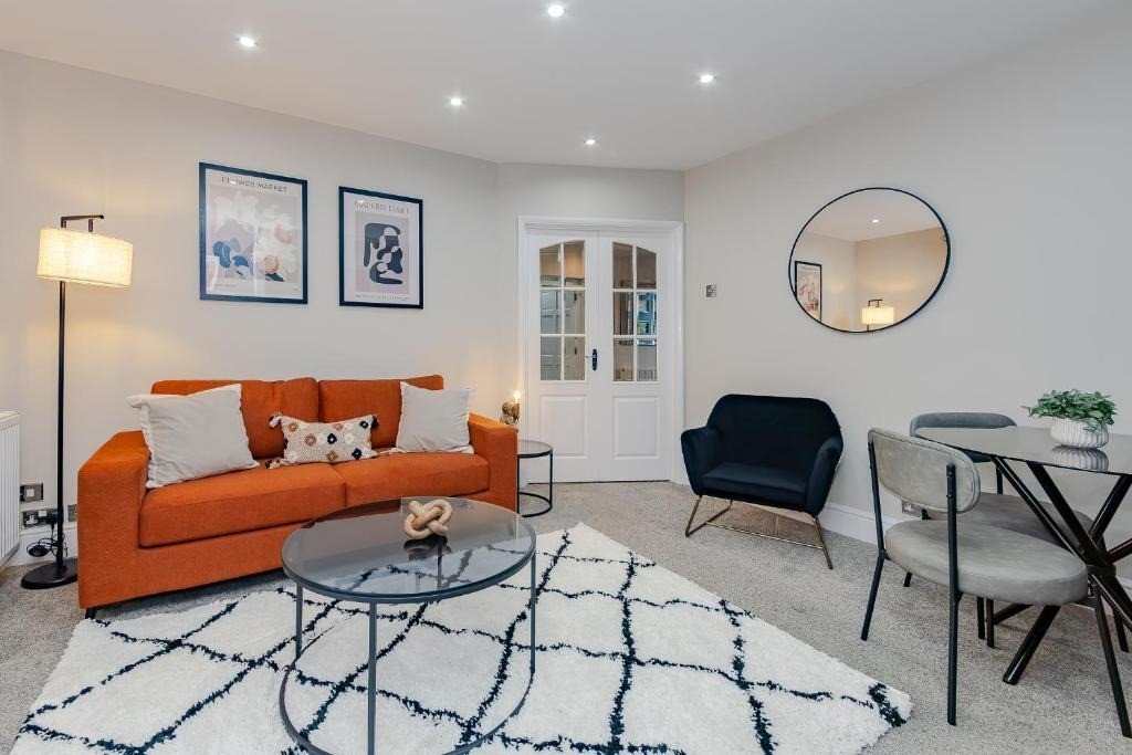 Modern living room with orange sofa, black armchair, glass coffee table and geometric rug