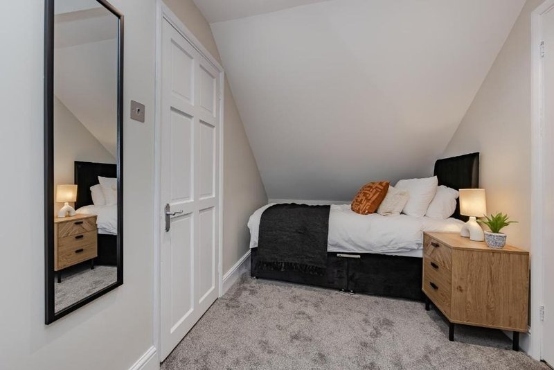 Bedroom with double bed, wooden bedside table, mirror, and sloped ceiling