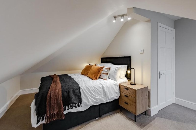 Attic bedroom with double bed, wooden nightstand, throw blankets and pillows