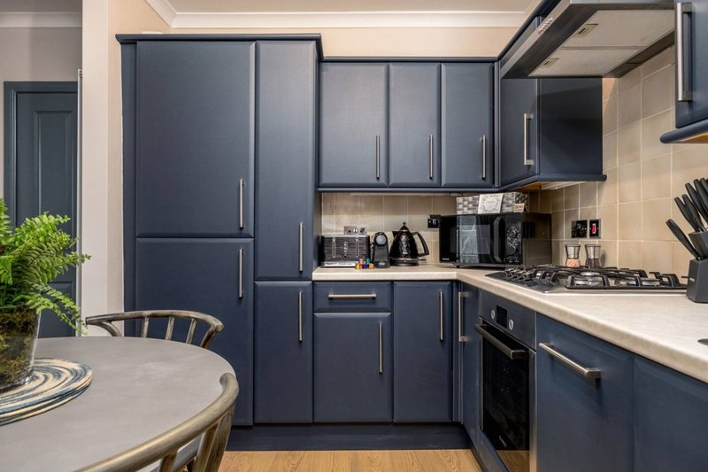 Modern kitchen with dark blue cabinetry, white countertop, gas hob, and dining table