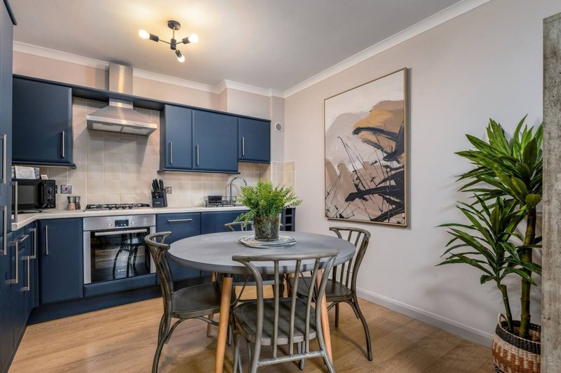 Modern kitchen with blue cabinetry, dining table, chairs, plants and wall art