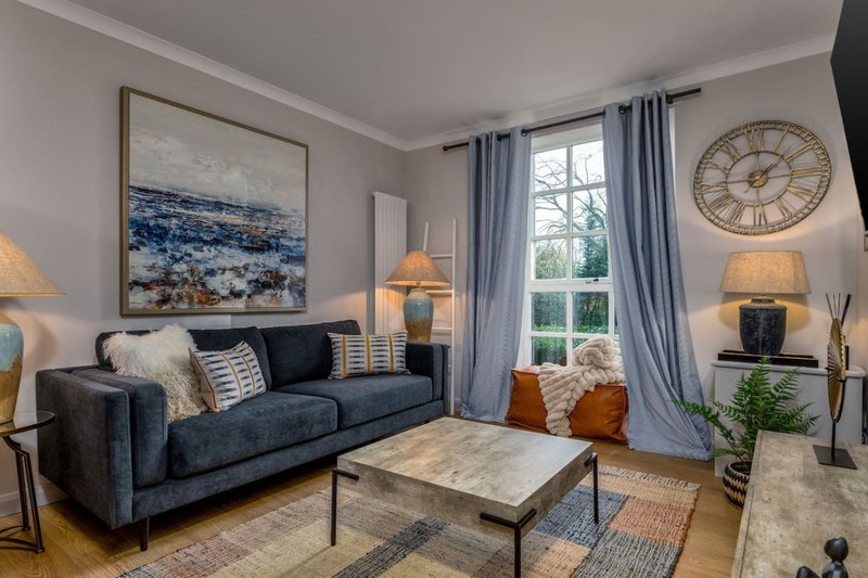 Modern living room with dark blue sofa, marble coffee table, large window with blue curtains