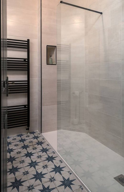 Modern bathroom with walk-in shower enclosure, heated towel rail, patterned floor tiles