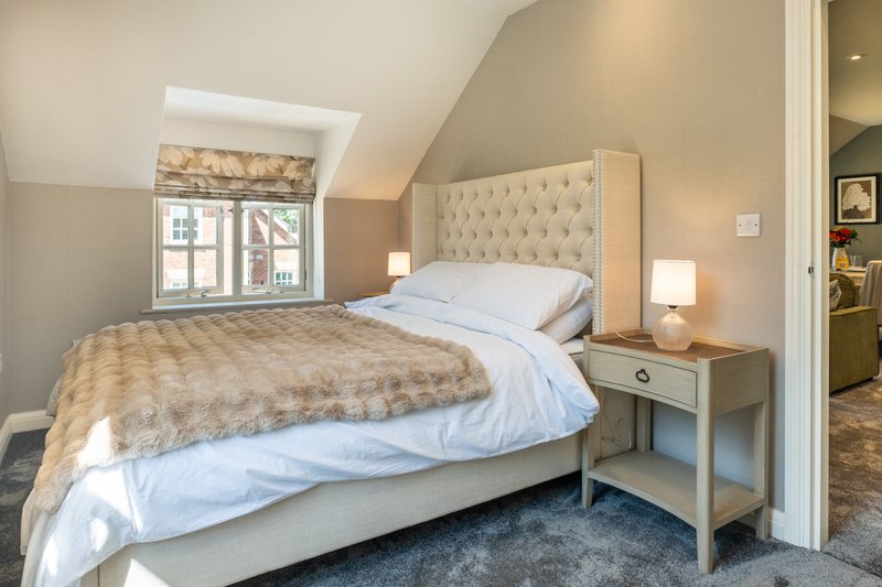 Bright bedroom with a comfortable king size bed and plush upholstered headboard, perfect for a peaceful night's sleep.