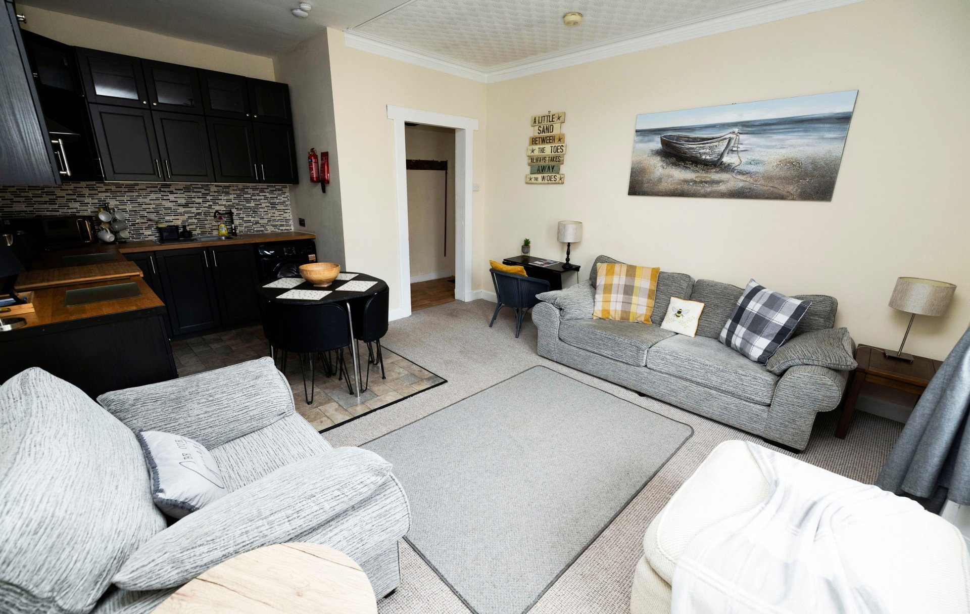 Open-plan living area with kitchen, dining table, and seating with landscape artwork