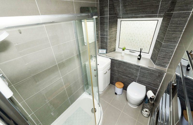 Modern bathroom with walk-in shower, toilet, sink and window with frosted glass
