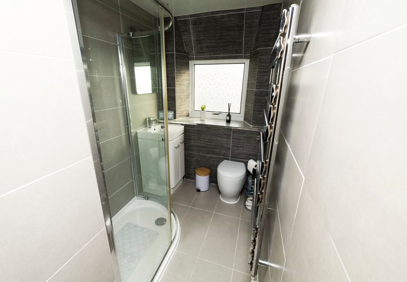 Compact bathroom with shower enclosure, toilet, sink and window