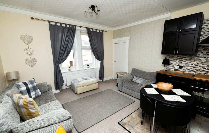 Living room with gray sofas, black TV unit, piano, and large window with gray curtains