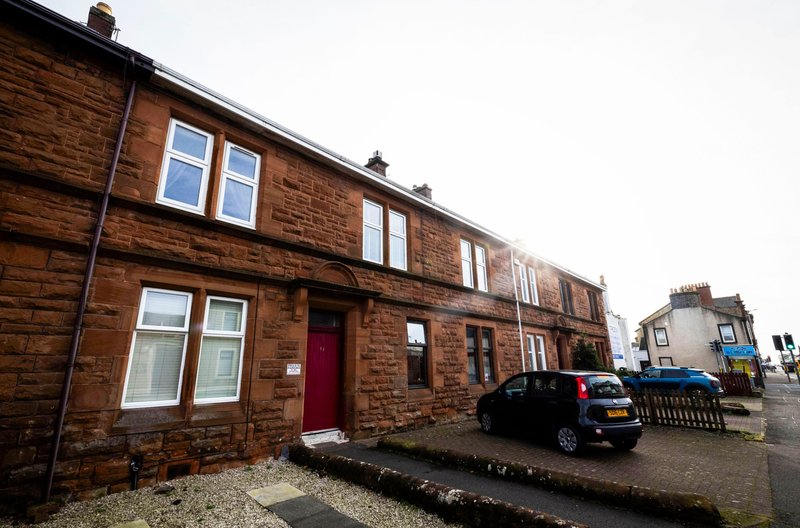 Red-brick terraced house with red door, white-framed windows and driveway