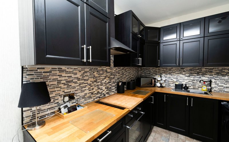 Modern kitchen with black cabinetry, mosaic tile backsplash and wooden countertops