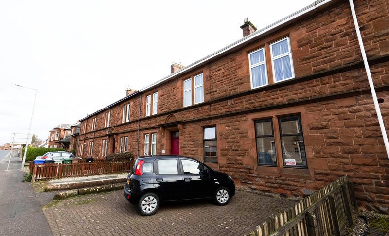 Red sandstone terraced building with parked car, driveway and street frontage