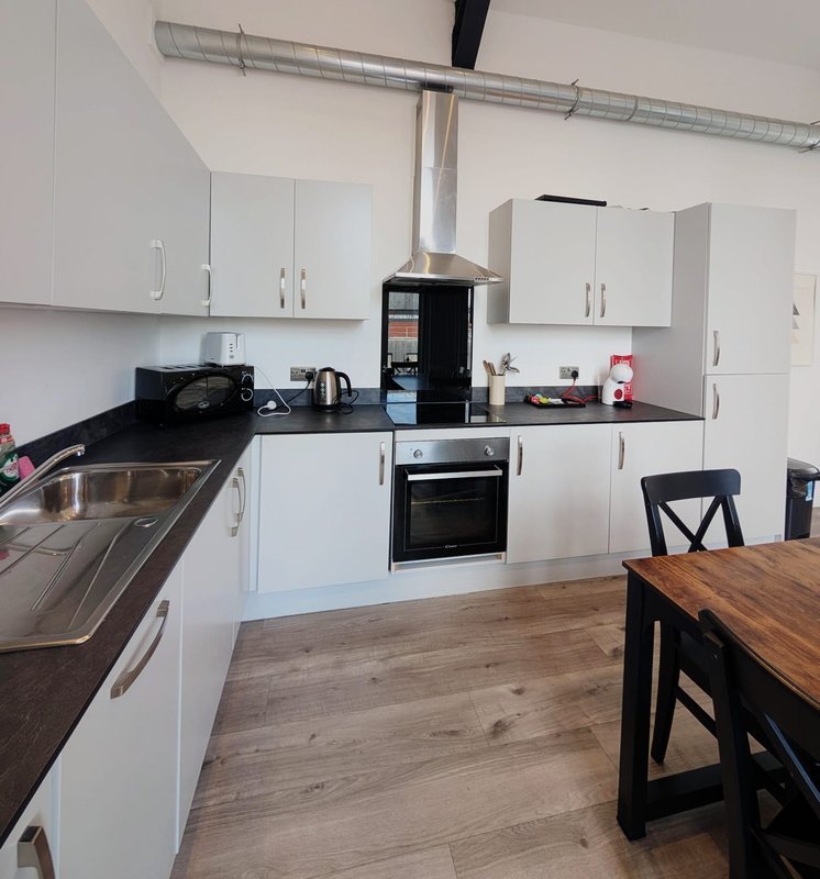 Modern kitchen with white cabinets, black countertops, stainless steel appliances and wooden dining table