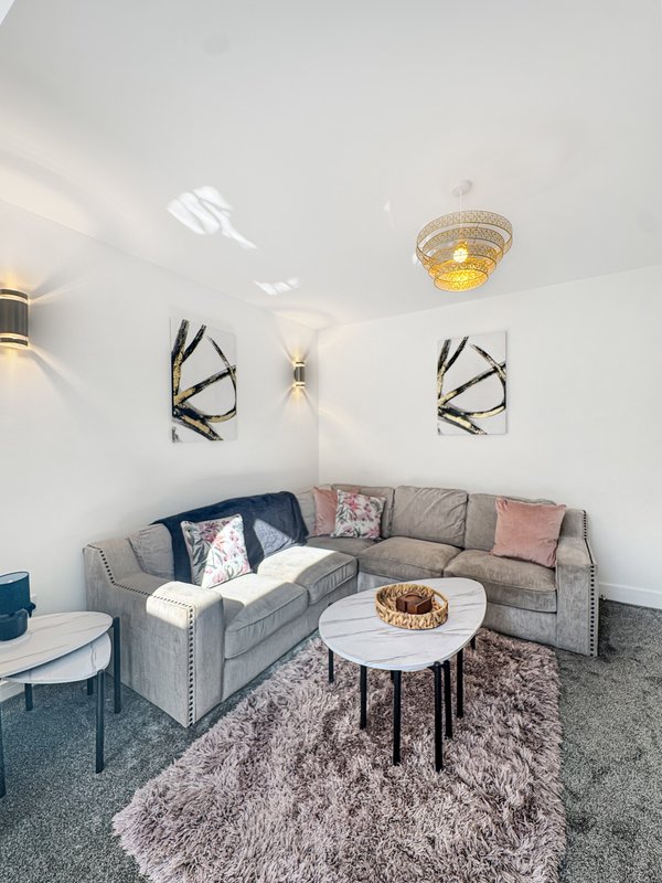 Modern living room with gray sectional sofa, white coffee table, geometric wall art, and soft furnishings