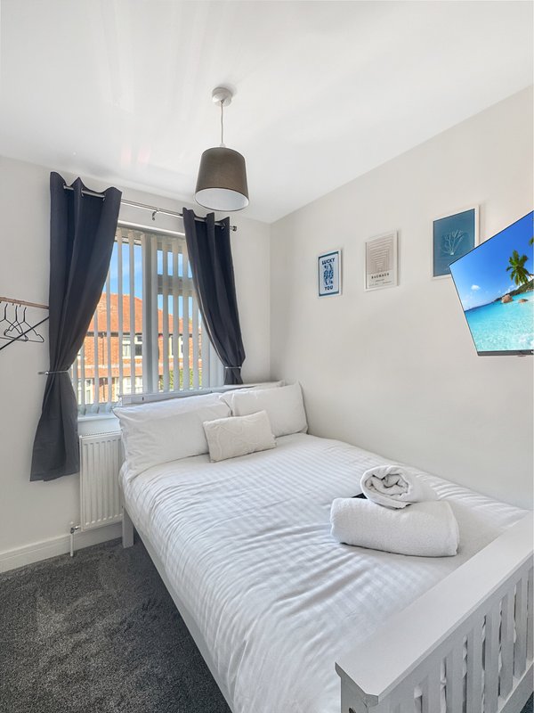 Compact bedroom with single bed, dark curtains, pendant lamp and framed wall art