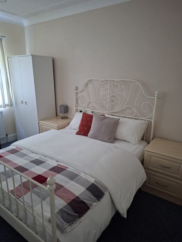 Bedroom with double bed, ornate headboard, plaid throw blanket, and wardrobe