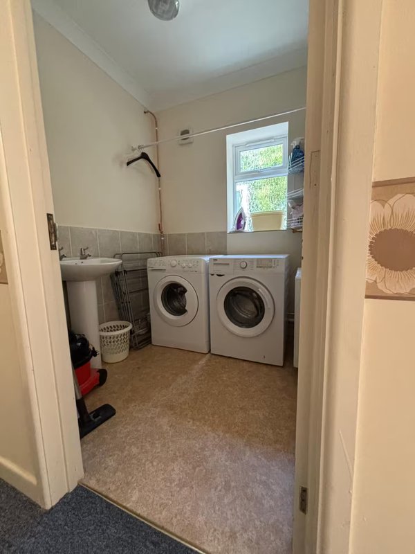Utility room with two washing machines, sink, window and laundry basket